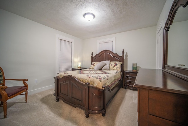 bedroom featuring light carpet, a textured ceiling, and baseboards