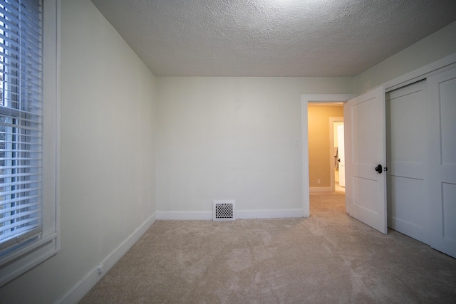 unfurnished bedroom featuring baseboards, a textured ceiling, visible vents, and carpet flooring