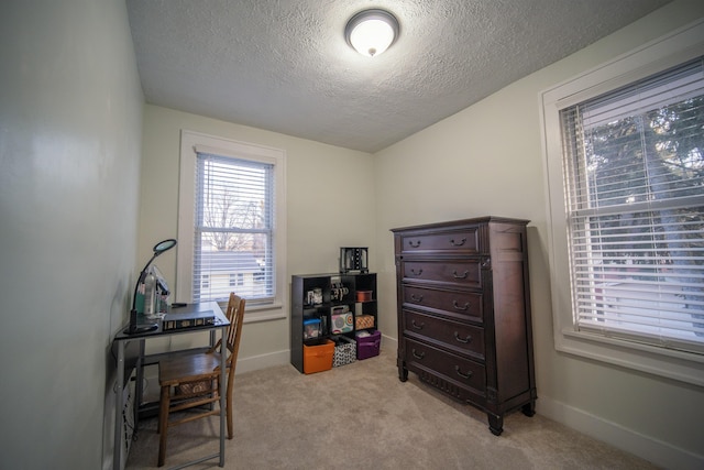 office area featuring light carpet, baseboards, and a textured ceiling