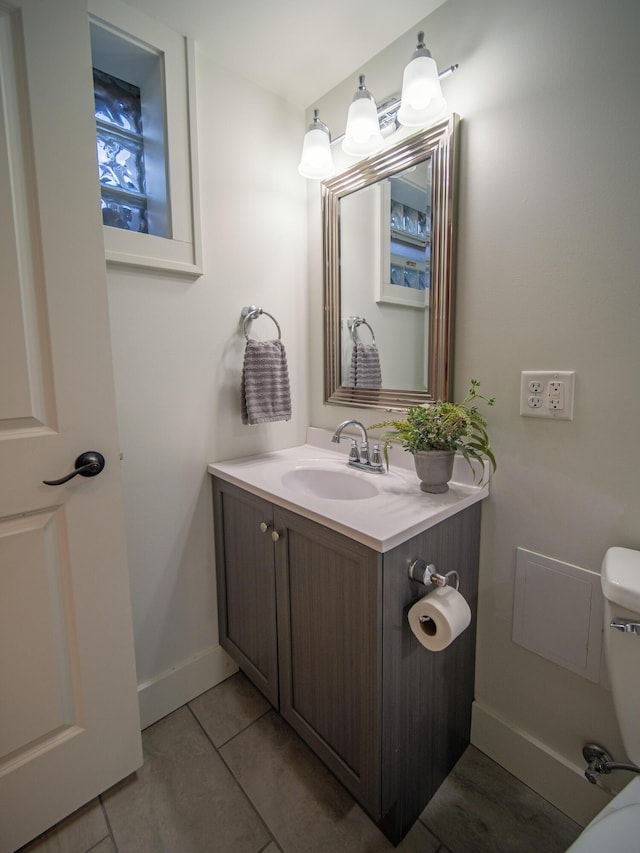 bathroom featuring toilet, tile patterned floors, baseboards, and vanity