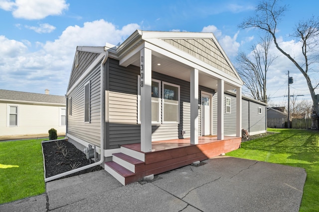 view of front of property with covered porch, fence, and a front lawn