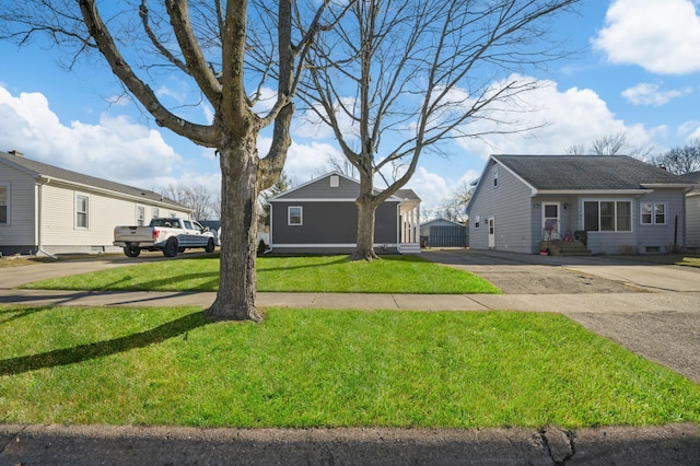 view of front facade featuring an outbuilding, driveway, and a front lawn