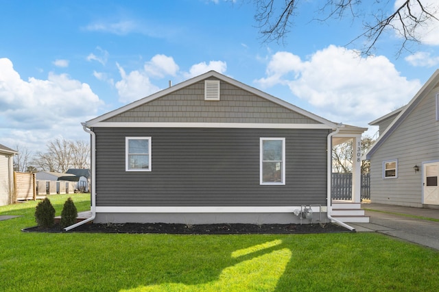 view of side of home featuring a lawn and fence