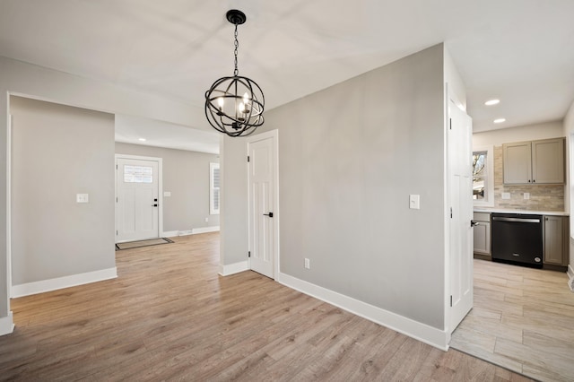 unfurnished dining area featuring light wood-style flooring, baseboards, a notable chandelier, and recessed lighting