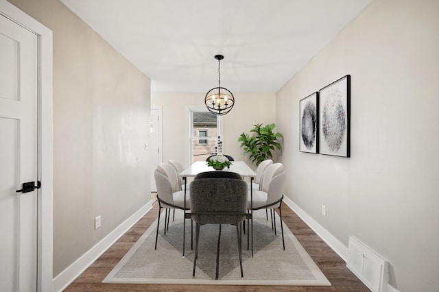 dining area featuring a notable chandelier, visible vents, baseboards, and dark wood-style flooring