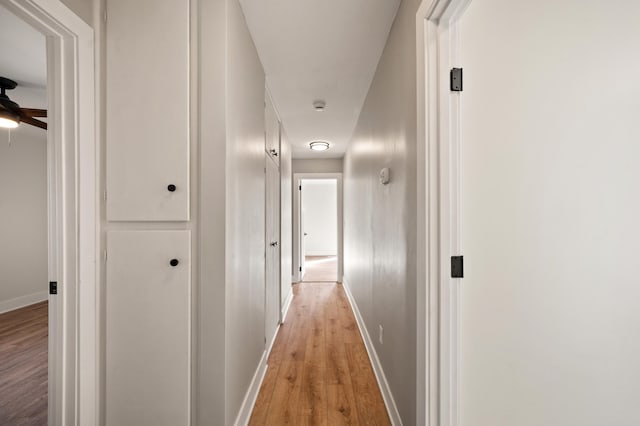 corridor with light wood-style flooring and baseboards