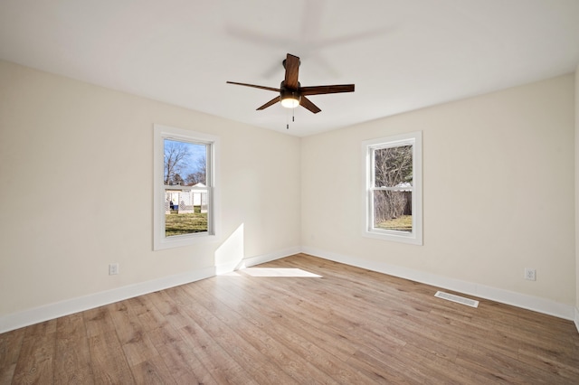 spare room with baseboards, visible vents, and wood finished floors