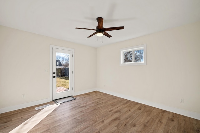 spare room with baseboards, wood finished floors, visible vents, and a healthy amount of sunlight