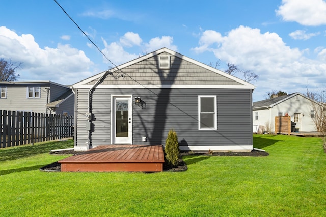 rear view of property with a yard, fence, and a wooden deck