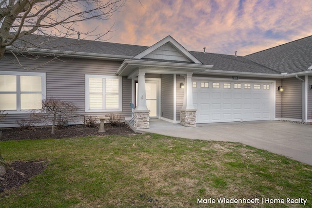 view of front of property featuring a yard, a shingled roof, an attached garage, stone siding, and driveway