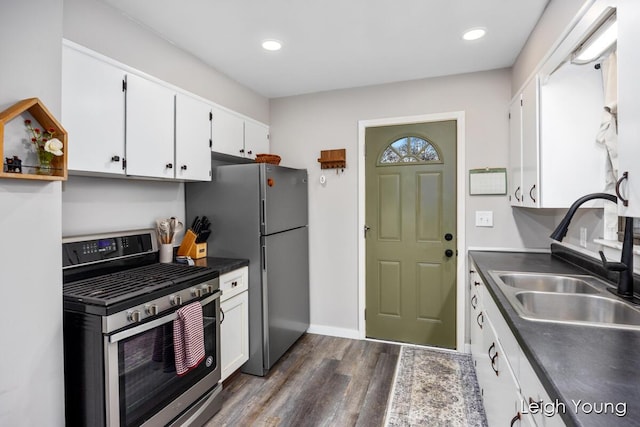 kitchen featuring dark wood-style floors, a sink, stainless steel appliances, white cabinetry, and dark countertops