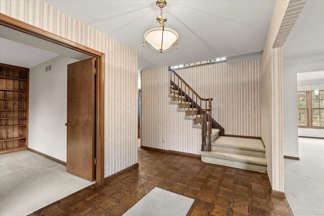 foyer entrance featuring baseboards, stairway, visible vents, and wallpapered walls