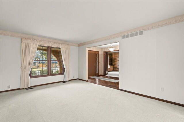 unfurnished room featuring carpet floors, visible vents, and baseboards