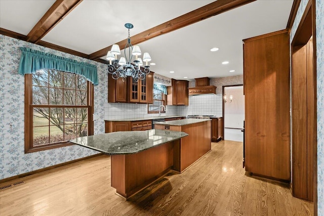 kitchen featuring light wood-style flooring, a kitchen island, visible vents, wallpapered walls, and an inviting chandelier