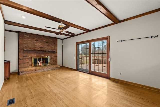 unfurnished living room featuring baseboards, visible vents, light wood-style flooring, a fireplace, and beam ceiling
