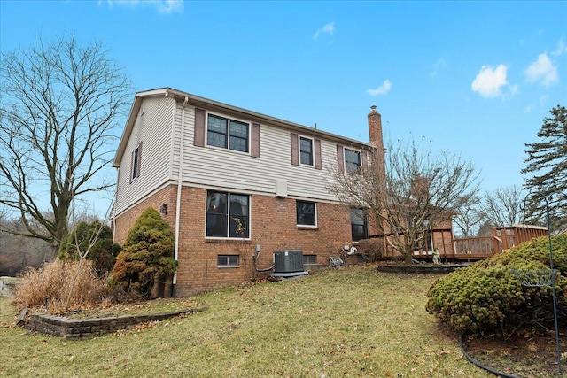 rear view of property with brick siding, a chimney, cooling unit, and a lawn