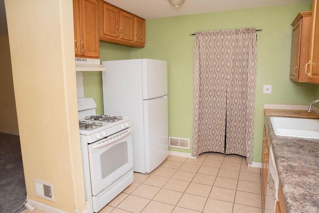 kitchen featuring white appliances, under cabinet range hood, visible vents, and a sink