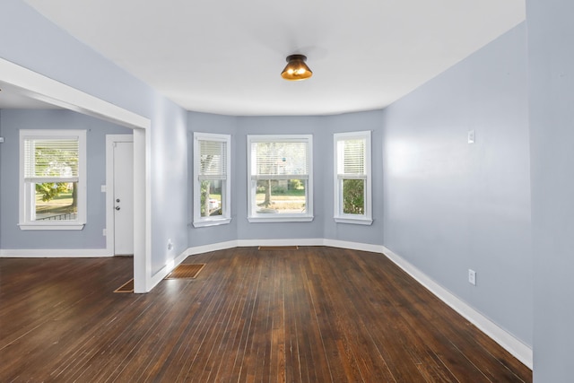 spare room with baseboards and hardwood / wood-style flooring