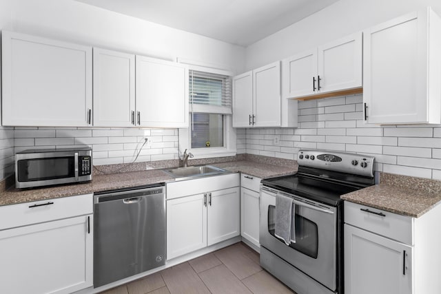 kitchen featuring appliances with stainless steel finishes, a sink, white cabinetry, and tasteful backsplash