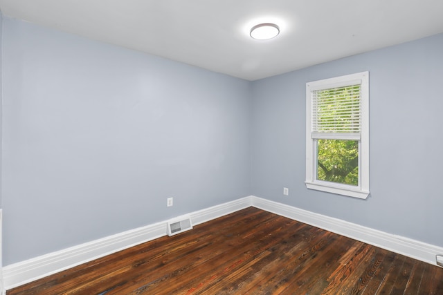 unfurnished room with dark wood-style floors, visible vents, and baseboards