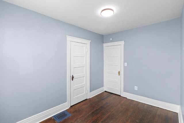 empty room featuring baseboards, visible vents, and dark wood finished floors