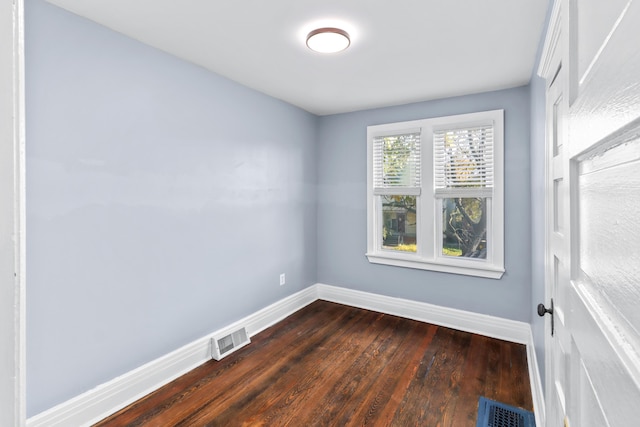 unfurnished room with baseboards, visible vents, and dark wood finished floors