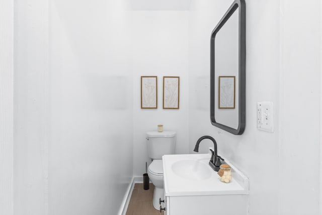 bathroom featuring baseboards, vanity, and toilet