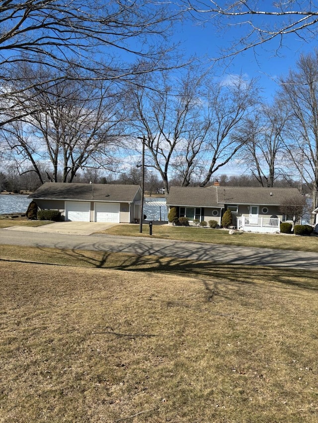 view of front of home featuring an outbuilding, a porch, a garage, driveway, and a front lawn