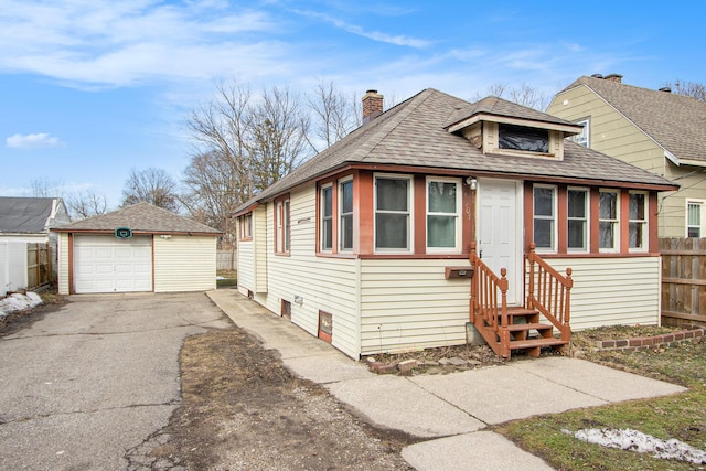 view of front of property featuring aphalt driveway, a chimney, fence, a garage, and an outdoor structure