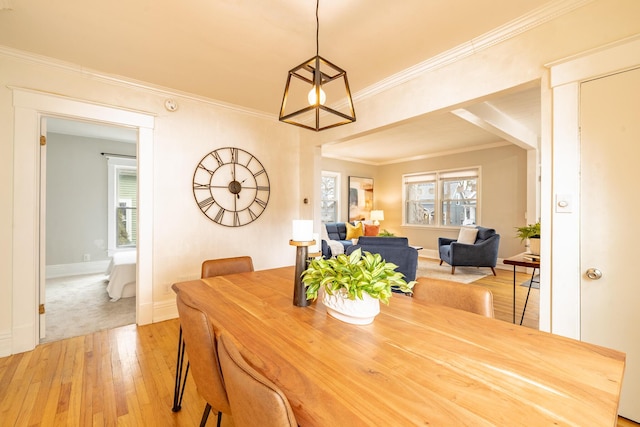 dining room featuring ornamental molding, light wood-type flooring, and baseboards