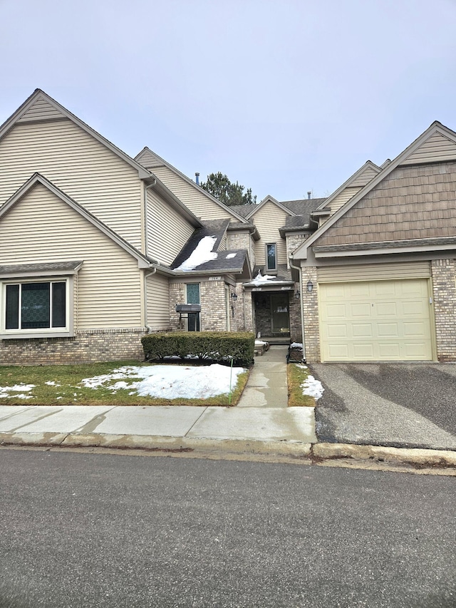 townhome / multi-family property featuring driveway, an attached garage, and brick siding