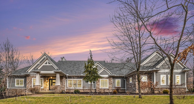 view of front of house featuring a yard, a chimney, and stone siding