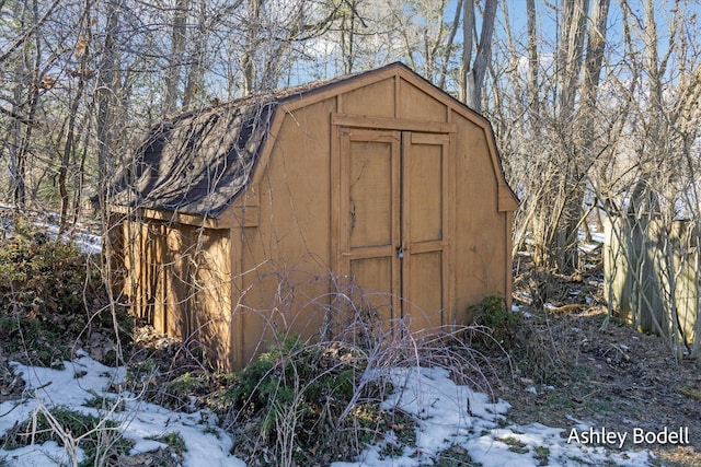 snow covered structure featuring a shed and an outdoor structure