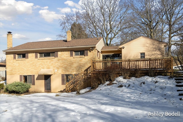 view of front of house with brick siding, a chimney, a wooden deck, and stairway