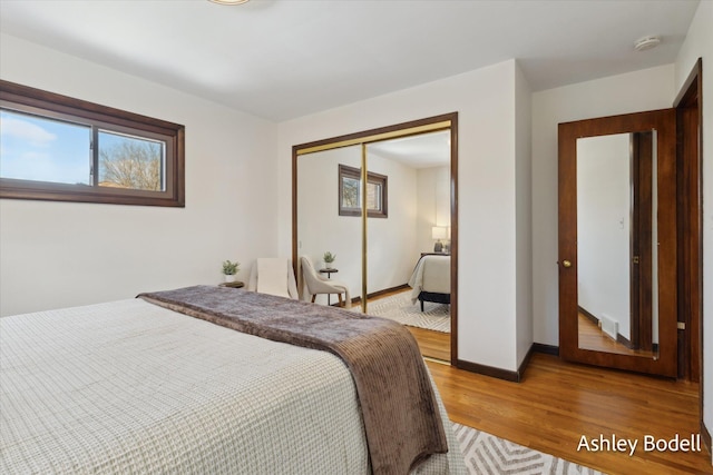 bedroom featuring a closet, light wood-style flooring, and baseboards