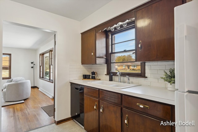 kitchen featuring freestanding refrigerator, a healthy amount of sunlight, dishwasher, and a sink