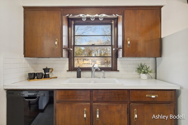 kitchen featuring dishwasher, decorative backsplash, a sink, and light countertops