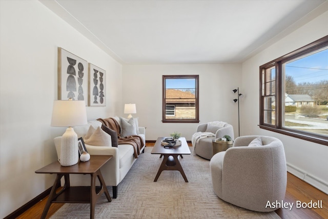 living room with a baseboard heating unit, wood finished floors, and baseboards