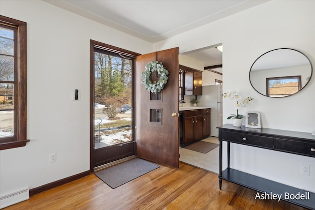 entrance foyer with a baseboard heating unit, light wood finished floors, and baseboards