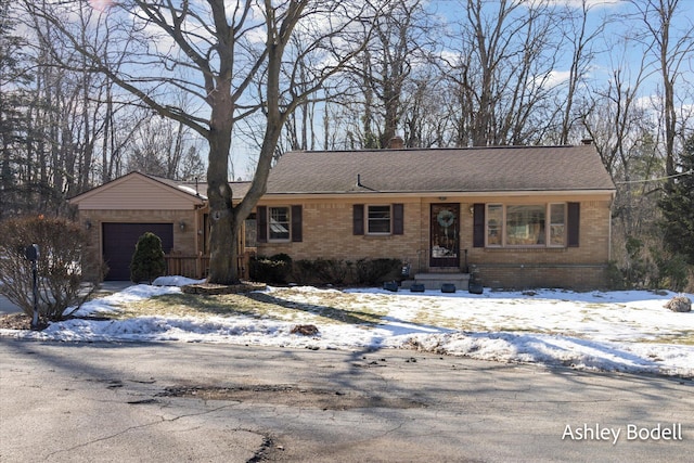 single story home featuring a garage, brick siding, roof with shingles, and aphalt driveway