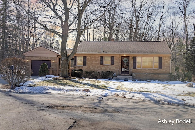 ranch-style home featuring driveway, brick siding, an attached garage, and a shingled roof