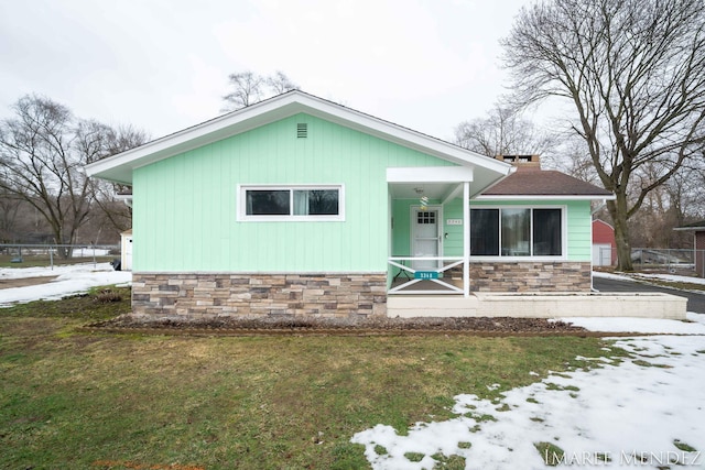 view of front of house with stone siding, a front lawn, and a chimney