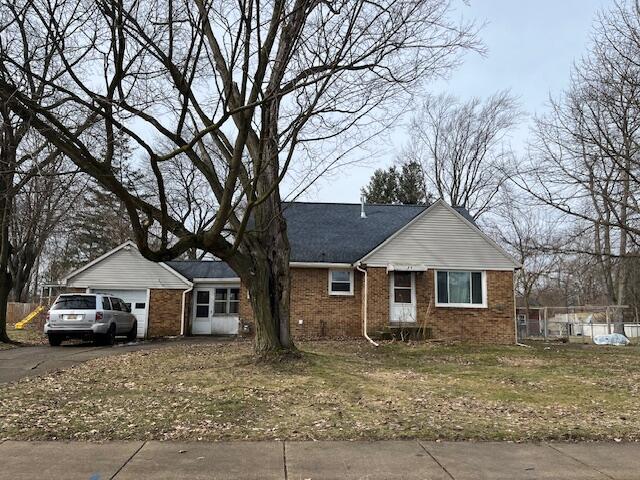 ranch-style home featuring driveway, an attached garage, fence, and brick siding