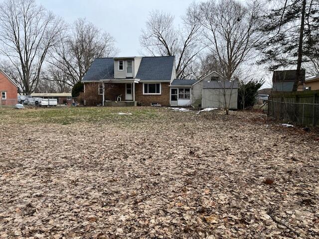 back of property with a garage, brick siding, and fence