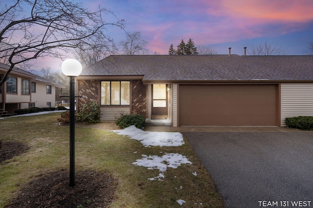 view of front of property with an attached garage, driveway, a shingled roof, and a front yard