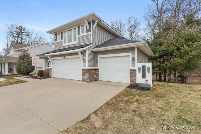 view of front of home featuring a garage, concrete driveway, stone siding, fence, and a front yard