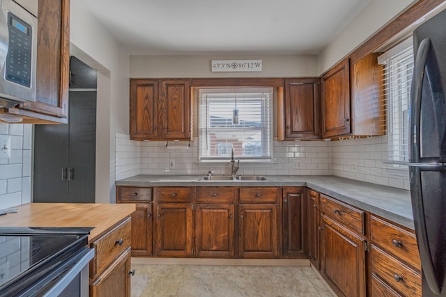 kitchen with tasteful backsplash, stainless steel microwave, a sink, and freestanding refrigerator