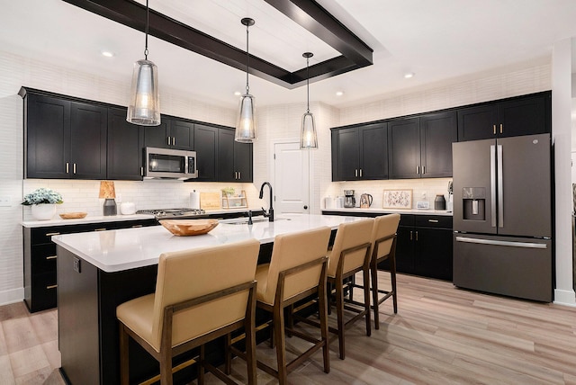 kitchen featuring a tray ceiling, stainless steel appliances, dark cabinetry, light countertops, and a sink