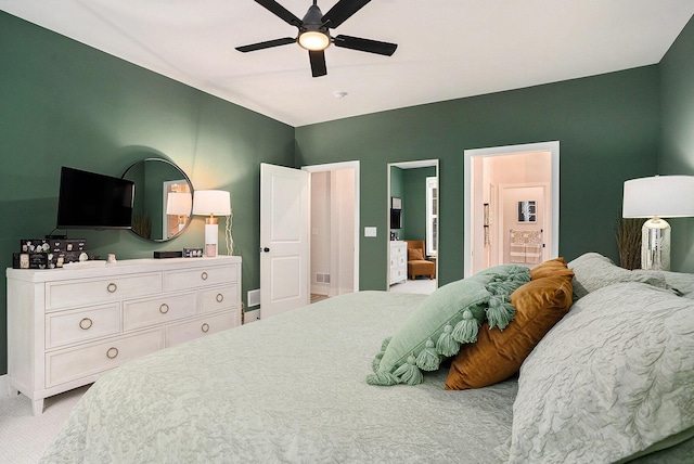 carpeted bedroom featuring ensuite bath, visible vents, and a ceiling fan
