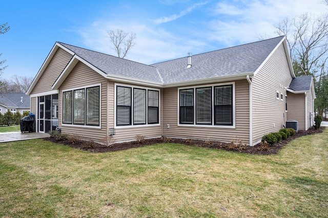 rear view of property with a shingled roof, a lawn, and central AC unit